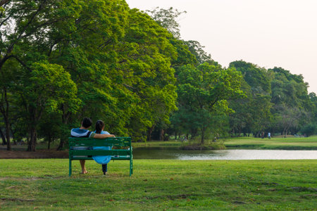 Sweet adult couple sitting together on a bench. They are relaxing in a park.の写真素材