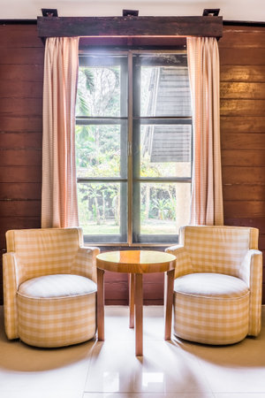 Classic twin fabric sofas and wooden round table. Interior design with window and curtains.のeditorial素材