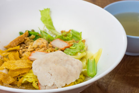 Dish of egg noodle with meat and red roasted pork. It is served with crispy wonton and a bowl of clear soup.の写真素材