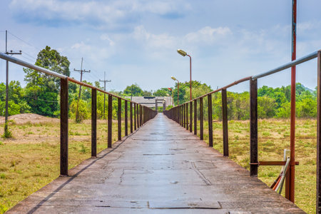 Old long iron bridge over grass field. It is in Phang Nga, Thailand.の写真素材
