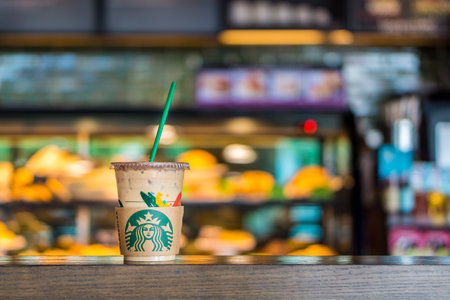 BANGKOK, THAILAND - JULY 2, 2017: Starbucks plastic cup with straw of Iced Caffe Espresso Beverage on table in coffeeshop. Starbucks is an American coffee company and coffeehouse chain.のeditorial素材