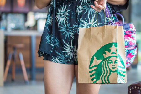 BANGKOK, THAILAND - JULY 2, 2017: Woman is holding Starbucks paper bag. Starbucks is an American coffee company and coffeehouse chain.のeditorial素材