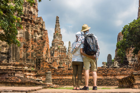 Romantic couple, European and Asian, embracing each other at old temple ruins. Foreign tourists go sightseeing in Ayutthaya Historical Park, Thailand, Southeast Asia.の写真素材