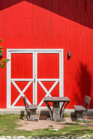 Natural vintage wooden table and benches. They are in front of retro farm barn.の写真素材