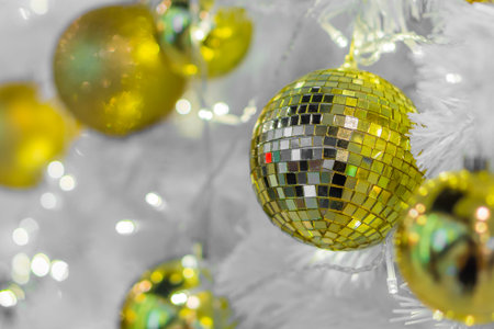 Glass Christmas baubles on white branches. Lights and spherical decorations are used to festoon a tree.の写真素材