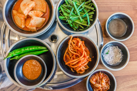 Top view of Korean side dishes filled with rich flavors, fresh and pickled vegetables. They are separated in small plates or bowls.の写真素材