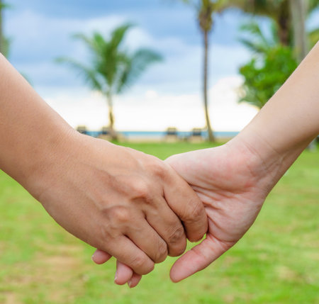 Hand in hand of couple near a beach. Right and left hand is Asian man and woman respectively.の写真素材