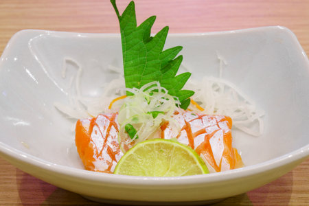 Bowl of Sashimi garnished with green shiso leaf, sliced lemon  and white shredded radish. It is a formal Japanese meal and delicacy.の写真素材