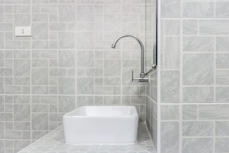 Side view of new modern grey restroom. It consists of mirror, ceramic wash basin, countertop and curve faucet.の写真素材