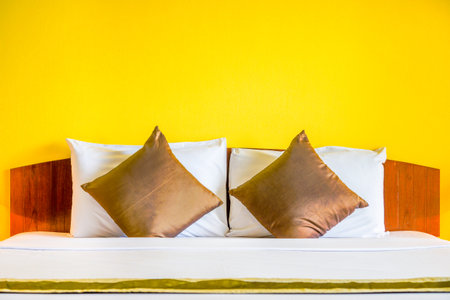 Interior decoration of romantic plain yellow bedroom. It consists of bed, white pillows and gold cushions.の写真素材