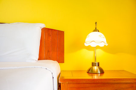 Vintage lamp on side table beside a bed in yellow room. The lighting in romantic bedroom.の写真素材