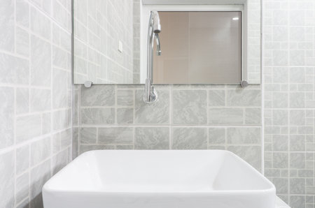 Front view of new modern grey restroom. It consists of mirror, ceramic washbasin and curve faucet.の写真素材