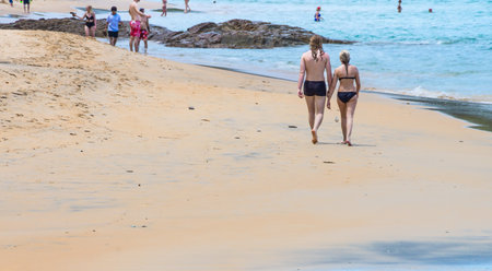 Couple in swimming suits walking on a beach. Tourist seaside attraction of Andaman sea in Thailand.の写真素材