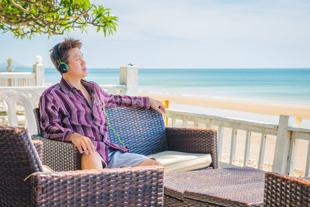 Man looking at sea and listening to music at seafront terrace. Scenery view of Hua Hin sea beach in Prachuap Khiri Khan, Thailand.の写真素材