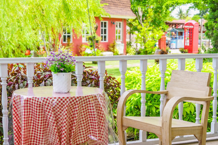 Vintage wooden armchair and table with flower vase. They are on a porch for relaxation and recreation.の写真素材