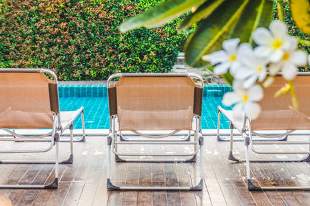 Rear view of aluminium sun loungers on decks at the side of swimming pool. For relaxation and recreation in hotel resort.の写真素材