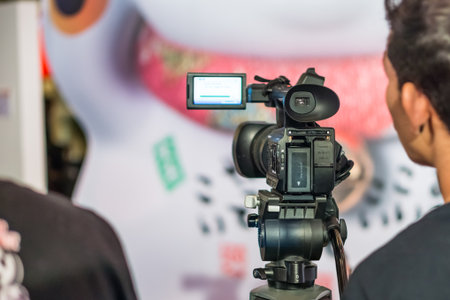 Digital camcorder on a tripod. It is operated by cameraman.
