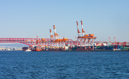 OSAKA, JAPAN - MAR 10, 2019: Cranes and cargo container ship near Minato Bridge. They are at sea port in Osaka bay, Japan.のeditorial素材