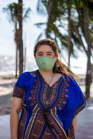 Woman wearing a green fashion face mask to prevent COVID-19. It is a DIY mask made of cloth with floral pattern.の写真素材