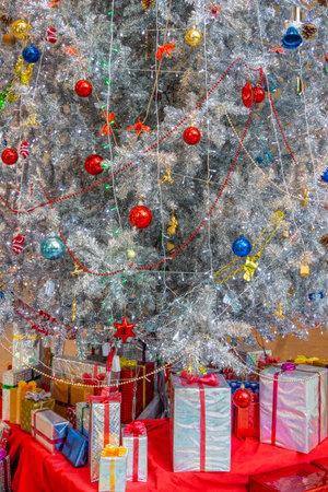 Christmas ornaments on artificial tree and gift boxes. Lights, spherical, star, baubles and other decorations are used to festoon the celebration.の写真素材
