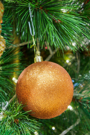 Golden glitter bauble decorated on Christmas tree. Spherical decoration are used to festoon artificial Xmas tree.の写真素材