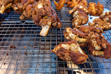 Crispy Fried Pork Knuckles - Thai Street Food Delight. The golden-brown crust, crunchy texture, deep-fried pork knuckles freshly prepared and displayed on a wire rack at market.の写真素材