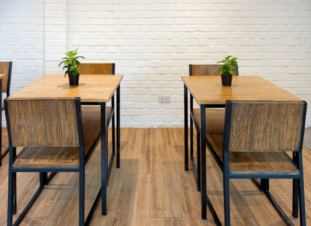 Minimalist Cafe Seating with Wooden Tables and Metal Framed Chairs. A modern cafÃ© interior featuring simple white brick wall and wooden flooring create a warm and stylish atmosphere.の写真素材