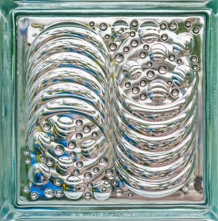 Textured Glass Block with Circular and Wavy Patterns. Decorative glass block featuring intricate patterns of raised circles and wavy lines, creating unique of light and reflectionの写真素材