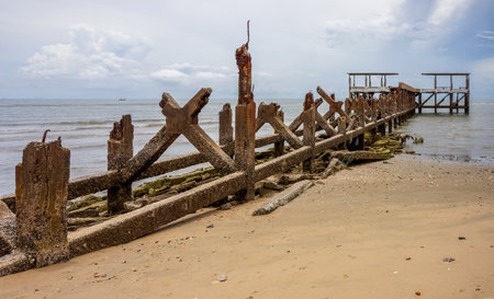 Remnants of old concrete pier on sandy beach. Atmospheric shot of the decaying remains of concrete...