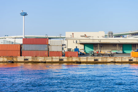 Shipping Containers and Warehouse at Osaka Bay Commercial Port, Japan. Stacked multi-colored cargo...
