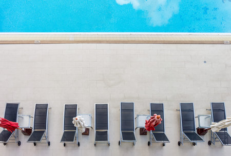Aerial Top View of Luxury Swimming Pool Deck with Sun Loungers and Umbrellas. High-angle shot of...