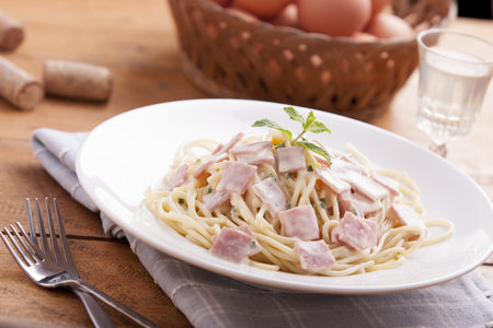 Spaghetti Carbonara on a white plate with hamの写真素材