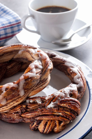 Chocolate pretzel served on a white plate with black coffee の写真素材