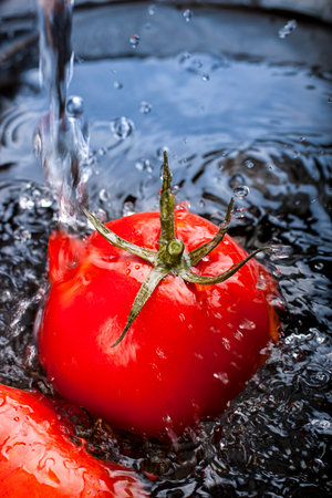 Closeup of washing tomatoes in the kitchen before cooking の写真素材