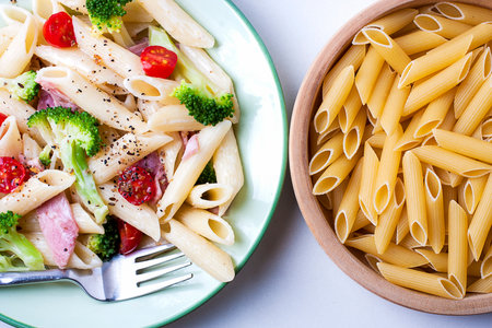 Colorful healthy pasta and raw pasta in a wooden dish.の写真素材