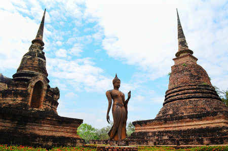 Buddha standing between two pagodas, blue sky.の写真素材