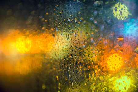 Seasonal scene, Rain drops on window glasses with bokeh background, selective focus on raindrops foreground and blur city lighting at night. romantic background lowkey lighting and effect filter.の写真素材