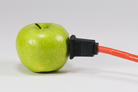 A green apple with an electrical cord plugged into itの写真素材
