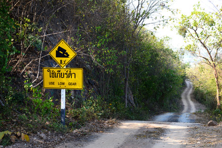 Downhill dust road with thai road signの写真素材