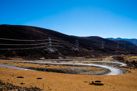 Road and High volt pole transmission tower in borders Xinjiang, Qinghai between Sichuan and Yunnan provinces in Chinaの写真素材