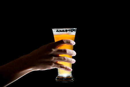 Hand holding glass of craft beer on black backgroundの写真素材