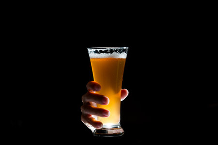 Hand holding glass of craft beer on black backgroundの写真素材