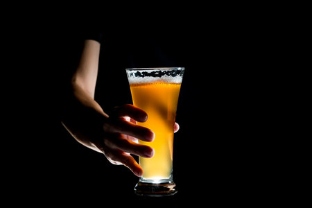 Hand holding glass of craft beer on black backgroundの写真素材