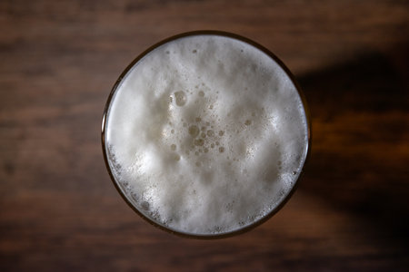 Top view glass of beer with bubble on blurred wooden tableの写真素材