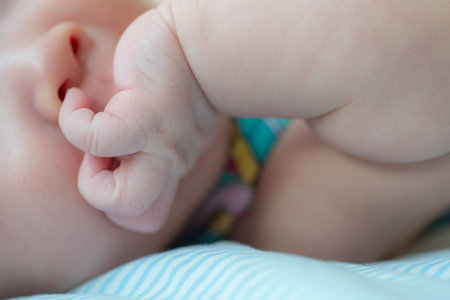 The picture captures a cute moment of a newborn baby attempting to explore by putting a finger in their nose, showcasing their curiosity and early motor skills developmentの写真素材