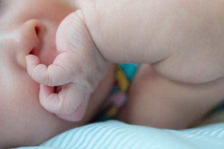 The picture captures a cute moment of a newborn baby attempting to explore by putting a finger in their nose, showcasing their curiosity and early motor skills developmentの写真素材