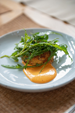 Indulge in a flavorful dinner with this crab cake recipe. Succulent crab cakes are paired perfectly with a fresh and peppery rocket salad, creating a delightful combination of tastes and textures.の写真素材