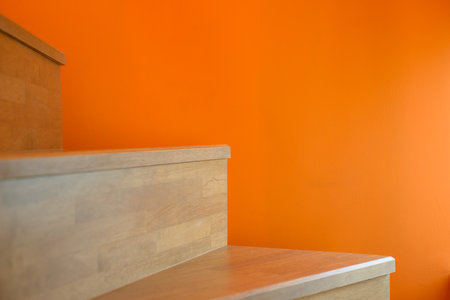 wooden stairs against an orange wall background, creating a visually striking contrast between natural and vibrant elements.の写真素材