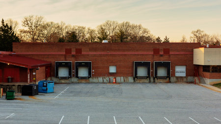 Establishing shot of an empty warehouse building with cargo loading dock and parking lot.の写真素材