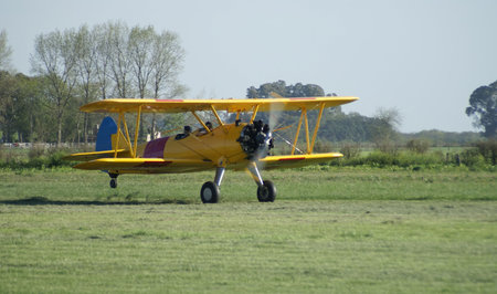 yellow vintage biplane taking off a field